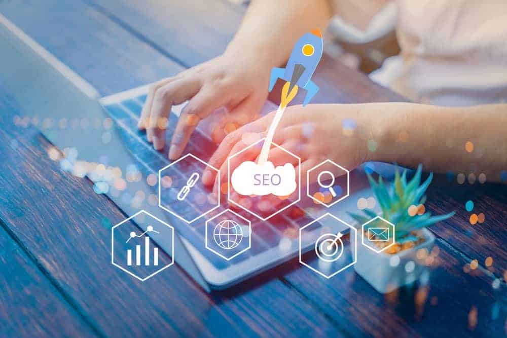 Hands typing on a laptop with SEO icons and a rocket, illustrating an NYC SEO Company in digital marketing.