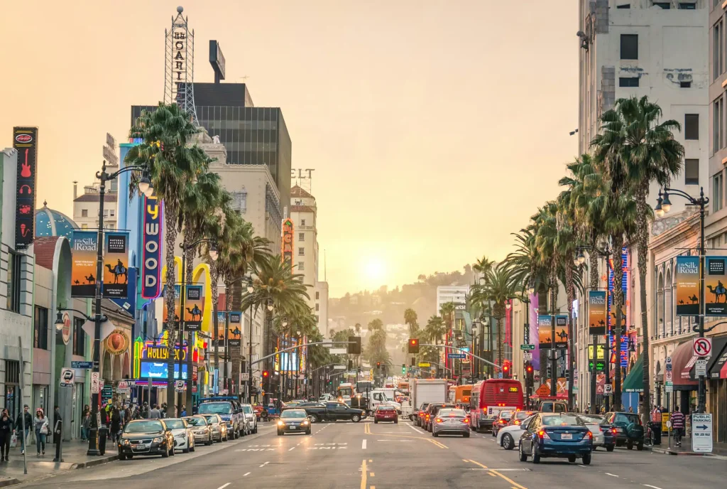 Sunset over a busy Hollywood street lined with palm trees and signs, including SEO Company NYC signage.
