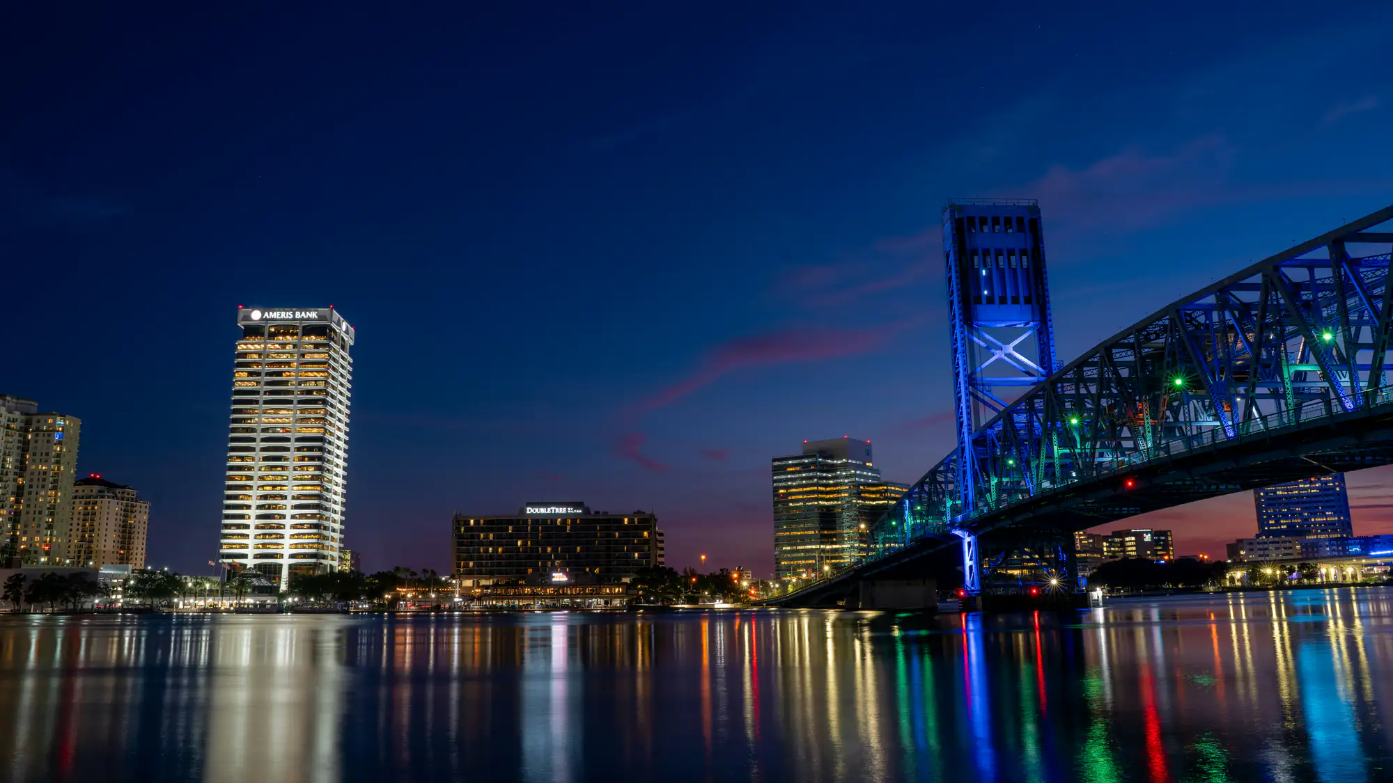 A nighttime city skyline features a lit bridge and buildings with "SEO Company NYC" reflected in the water.