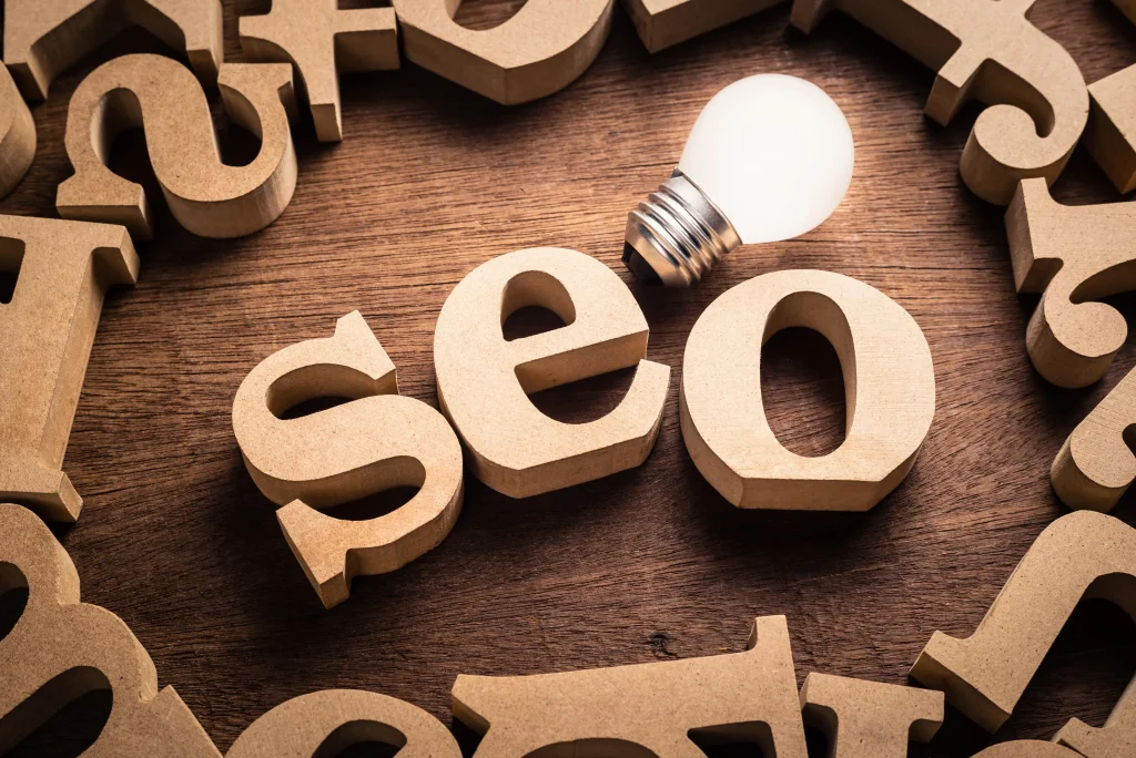 The letters “seo” arranged with wooden letters and a glowing bulb above suggest digital marketing focus.